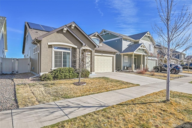 view of front of house featuring solar panels, fence, driveway, an attached garage, and a gate