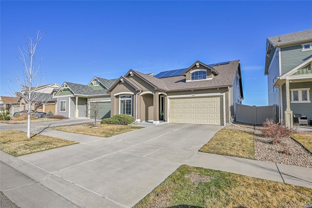 view of front of home with driveway, fence, roof with shingles, an attached garage, and solar panels