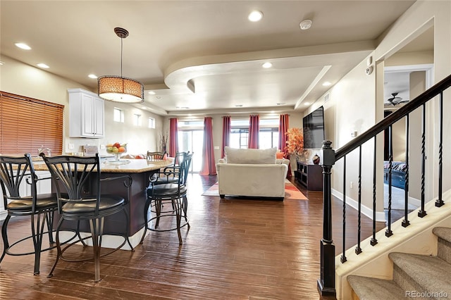 kitchen with recessed lighting, white cabinetry, a kitchen bar, and dark wood-style flooring