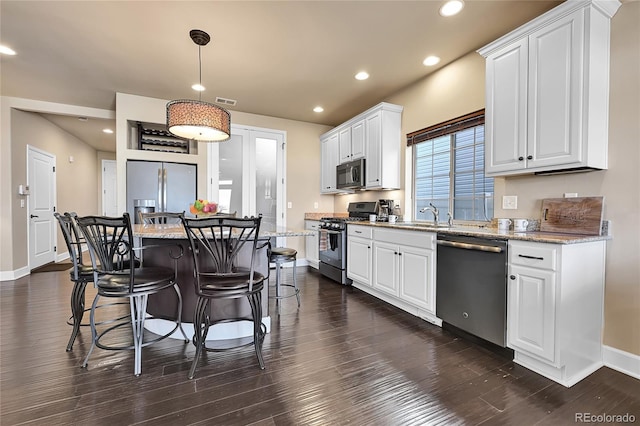 kitchen with a breakfast bar, white cabinetry, dark wood-style flooring, and appliances with stainless steel finishes