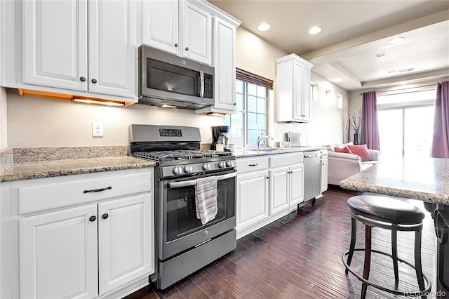 kitchen with dark wood finished floors, recessed lighting, appliances with stainless steel finishes, white cabinets, and light stone countertops