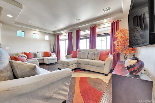 living room featuring visible vents, a raised ceiling, and wood finished floors