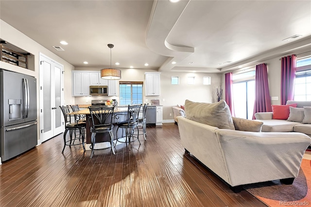 living area with recessed lighting, visible vents, dark wood-style flooring, and baseboards