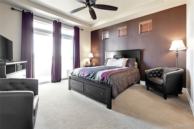 bedroom featuring a tray ceiling, carpet flooring, and ceiling fan