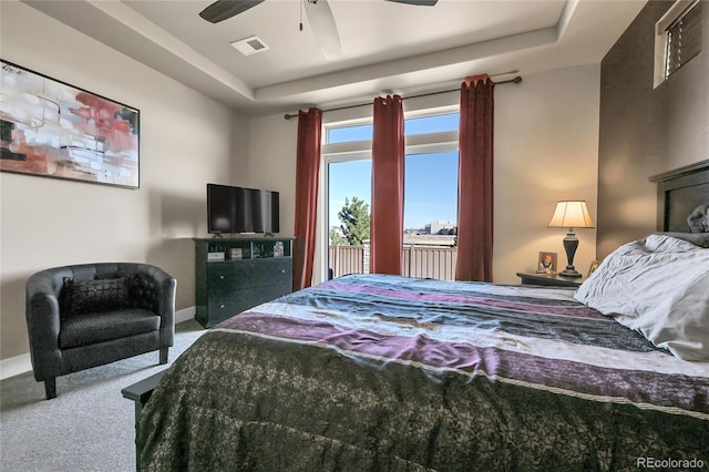 carpeted bedroom with visible vents, ceiling fan, baseboards, a tray ceiling, and access to outside