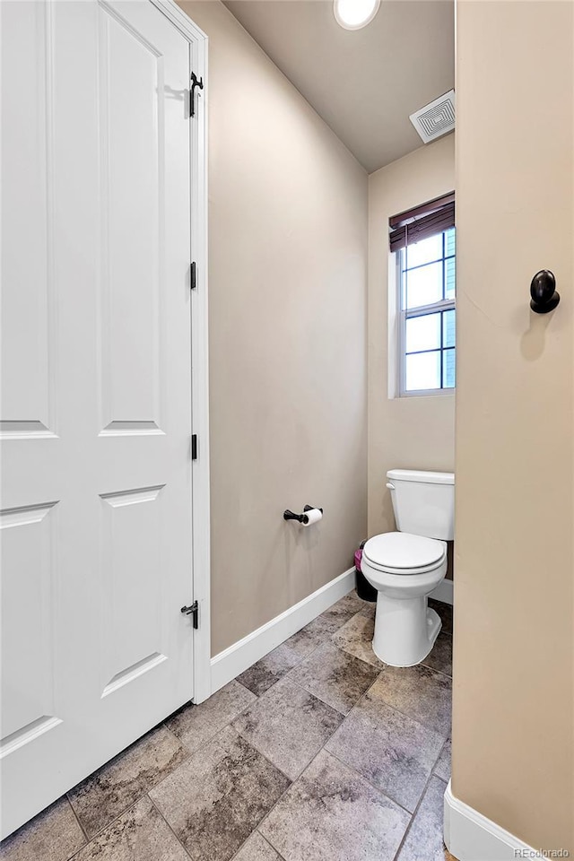 bathroom featuring visible vents, stone finish floor, toilet, and baseboards