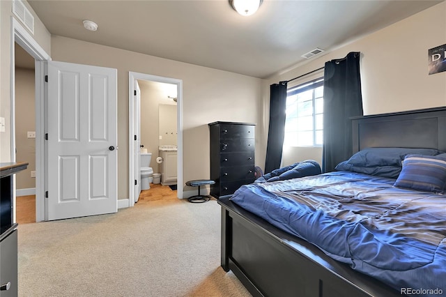 bedroom featuring baseboards, light colored carpet, visible vents, and connected bathroom