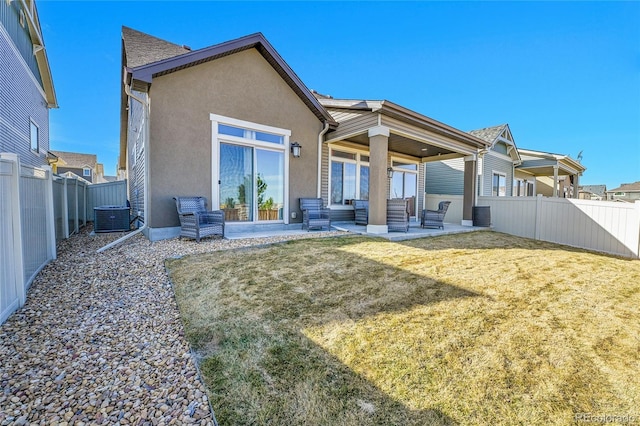 rear view of property featuring central AC unit, a yard, a fenced backyard, stucco siding, and a patio area