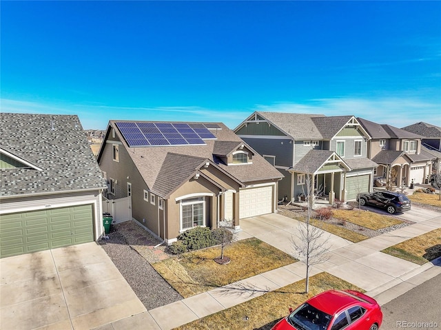 view of front of property featuring driveway, roof mounted solar panels, a residential view, an attached garage, and a shingled roof