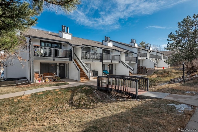 back of property with stairs, a lawn, and a residential view