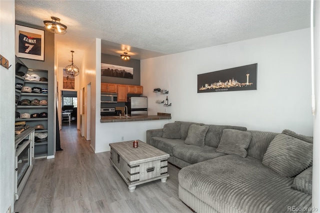 living area featuring an inviting chandelier, light wood finished floors, and a textured ceiling