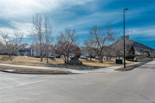 view of road with street lights, a mountain view, curbs, and sidewalks