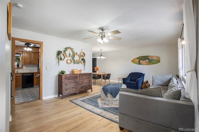 living room featuring ceiling fan with notable chandelier and light wood-type flooring