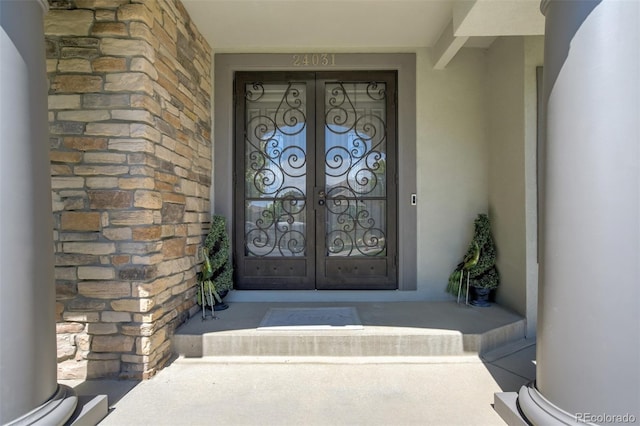 24031 E Hinsdale Pl, Aurora, CO 80016 - view of exterior entry with french doors, stucco siding, and stone siding