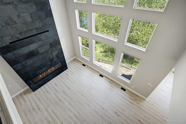 24031 E Hinsdale Pl, Aurora, CO 80016 - unfurnished living room featuring wood finished floors, a towering ceiling, healthy amount of natural light, a glass covered fireplace, and baseboards