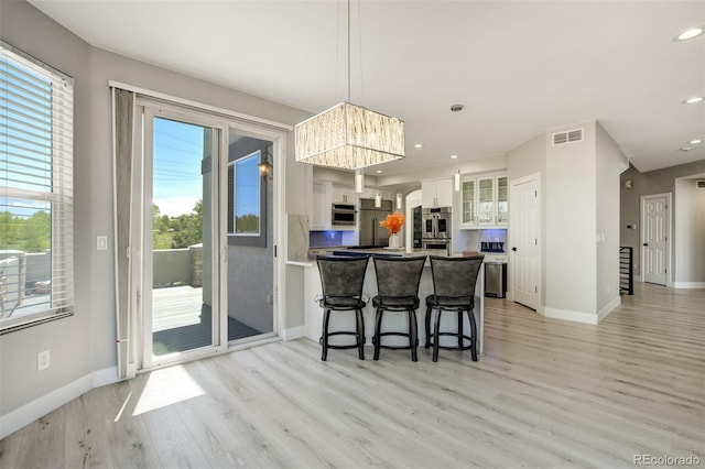 24031 E Hinsdale Pl, Aurora, CO 80016 - kitchen featuring white cabinets, appliances with stainless steel finishes, light wood-type flooring, a peninsula, and baseboards