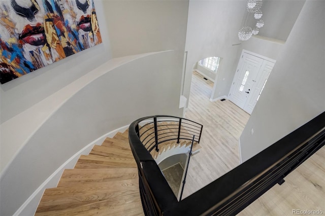 24031 E Hinsdale Pl, Aurora, CO 80016 - stairs featuring a chandelier, wood finished floors, a towering ceiling, baseboards, and arched walkways