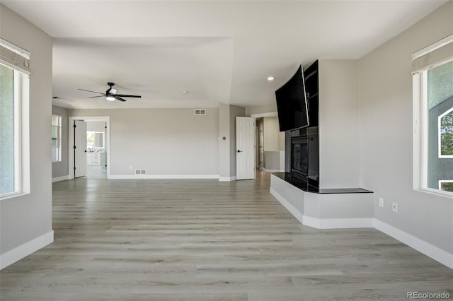 24031 E Hinsdale Pl, Aurora, CO 80016 - unfurnished living room with a glass covered fireplace, baseboards, light wood-type flooring, healthy amount of natural light, and recessed lighting