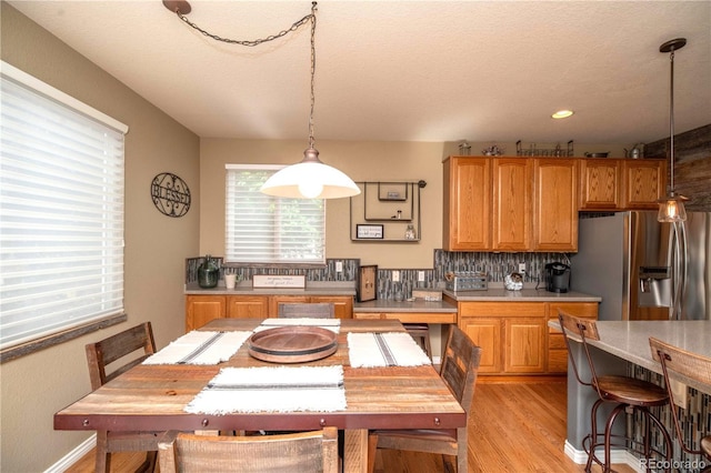 14962 Williams St, Thornton, CO 80602 - kitchen with stainless steel fridge with ice dispenser, light countertops, light wood finished floors, decorative light fixtures, and a textured ceiling