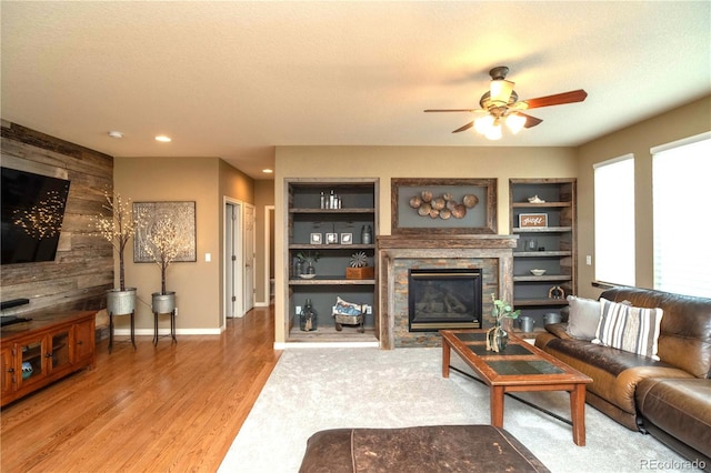 14962 Williams St, Thornton, CO 80602 - living room featuring ceiling fan, a glass covered fireplace, light wood-style floors, wooden walls, and built in features