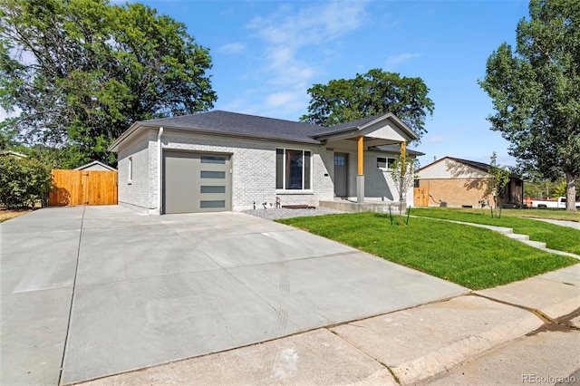 view of front of house with brick siding, concrete driveway, a front yard, fence, and a garage