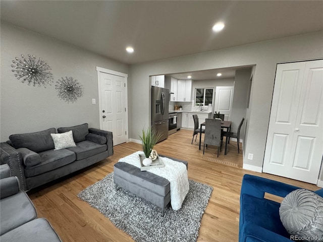 living room with light wood-style floors, recessed lighting, and baseboards