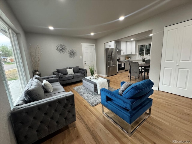 living room featuring light wood-type flooring, baseboards, and recessed lighting