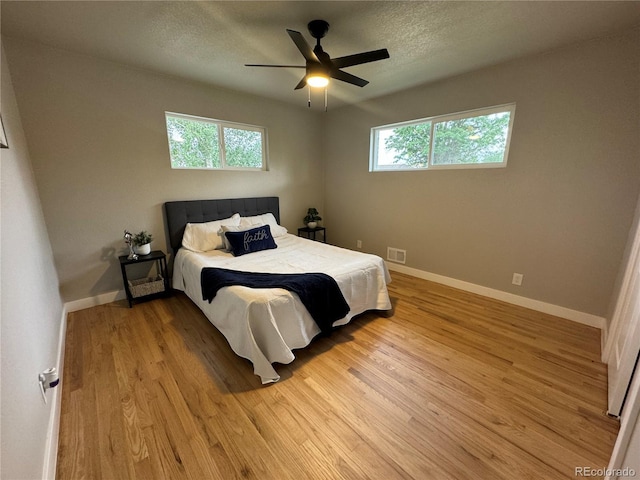 bedroom featuring a textured ceiling, visible vents, light wood-style flooring, and baseboards