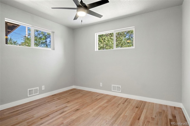 empty room featuring light wood-style floors, a healthy amount of sunlight, and visible vents