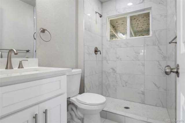 bathroom with toilet, tiled shower, and vanity