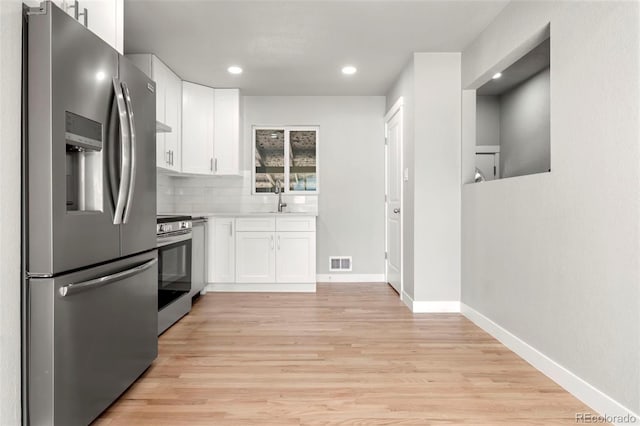 kitchen with light hardwood / wood-style flooring, white cabinets, backsplash, and stainless steel appliances