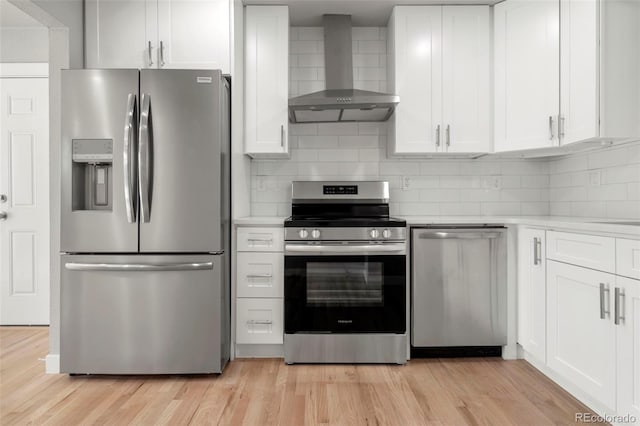 kitchen featuring stainless steel appliances, light countertops, wall chimney exhaust hood, and white cabinetry