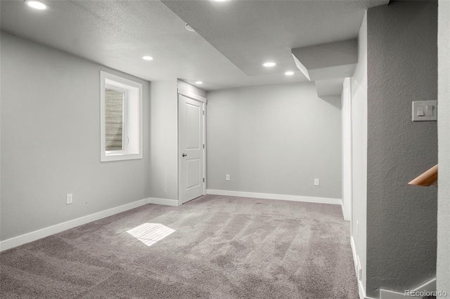 finished below grade area featuring light carpet, a textured ceiling, recessed lighting, and baseboards