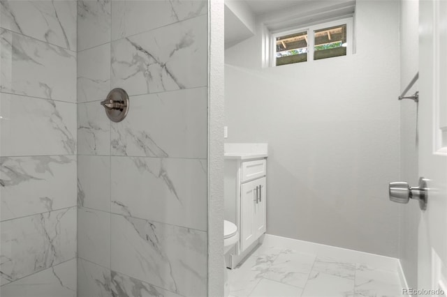 bathroom featuring marble finish floor, a textured wall, a tile shower, vanity, and baseboards