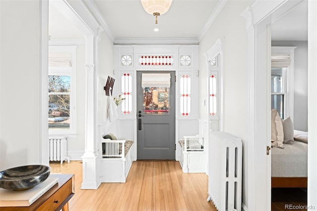 corridor with ornamental molding, radiator heating unit, and light hardwood / wood-style floors