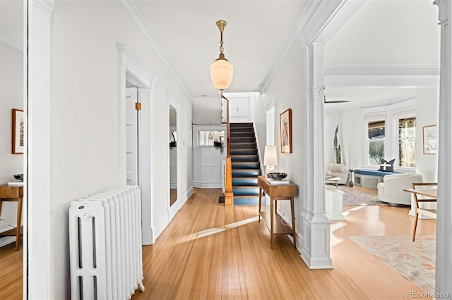 corridor with crown molding, ornate columns, radiator, and light wood-type flooring