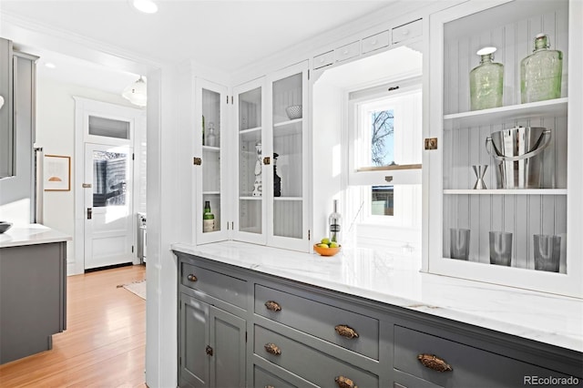 bar featuring light stone countertops, gray cabinetry, and light wood-type flooring