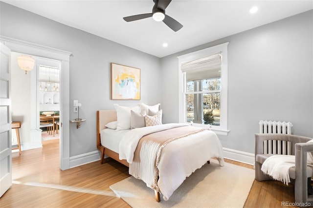 bedroom featuring hardwood / wood-style floors, radiator heating unit, and ceiling fan