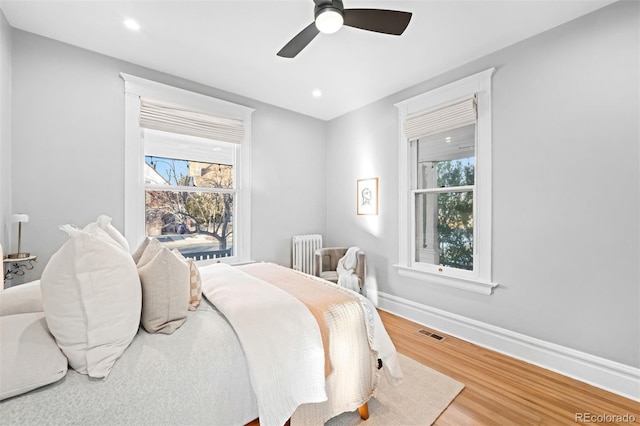 bedroom featuring hardwood / wood-style flooring, radiator, and ceiling fan