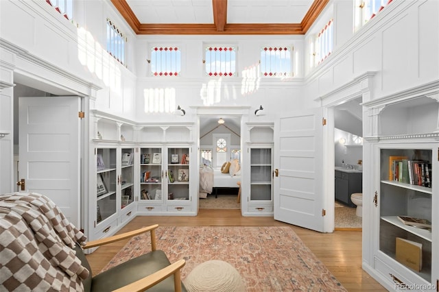 interior space with beamed ceiling, coffered ceiling, a healthy amount of sunlight, and light wood-type flooring