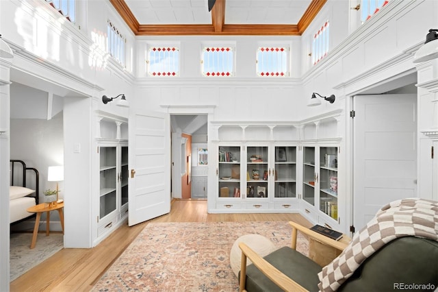 living room with coffered ceiling, crown molding, plenty of natural light, and light hardwood / wood-style floors