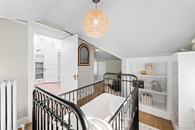 interior space featuring vaulted ceiling, radiator heating unit, and light hardwood / wood-style floors