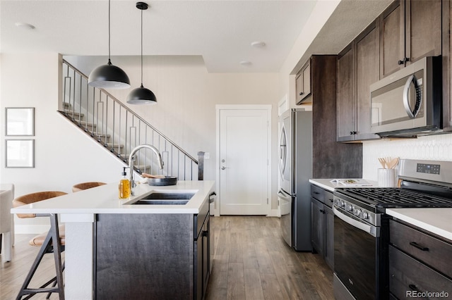 kitchen featuring a breakfast bar, sink, dark brown cabinets, pendant lighting, and stainless steel appliances