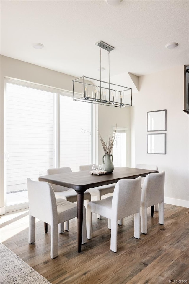 dining room featuring a healthy amount of sunlight, dark wood-type flooring, and a textured ceiling