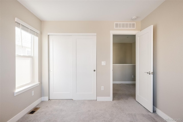 unfurnished bedroom with light carpet and a closet