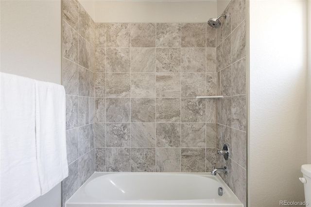 bathroom with tiled shower / bath combo and toilet