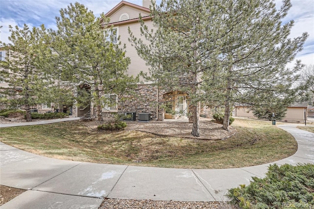 view of front of property featuring cooling unit and a front lawn