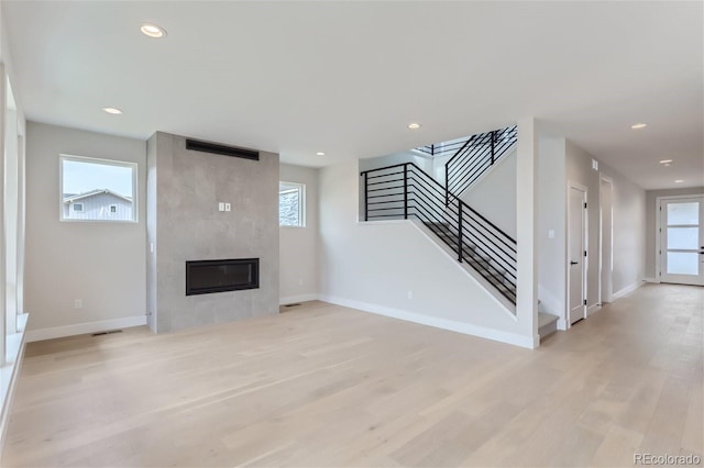 unfurnished living room featuring a wealth of natural light, a fireplace, and light wood-type flooring