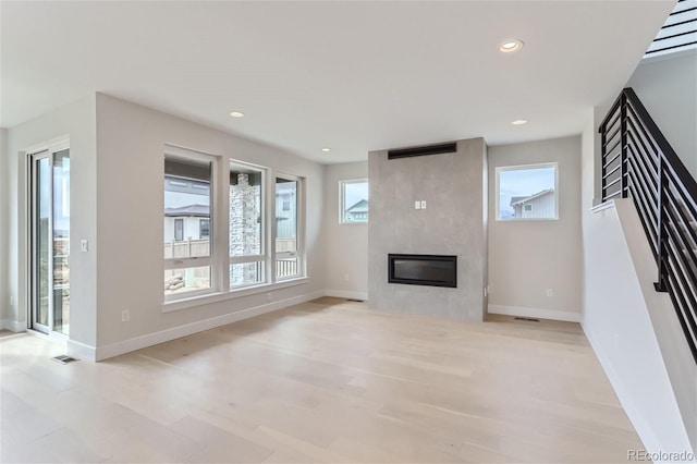 unfurnished living room featuring a tiled fireplace and light hardwood / wood-style flooring