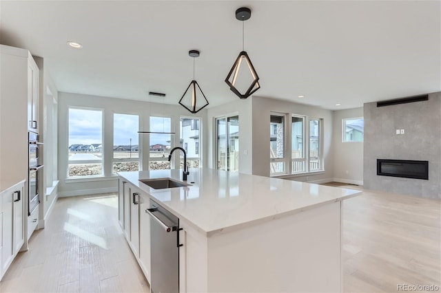 kitchen featuring white cabinetry, sink, pendant lighting, and a kitchen island with sink